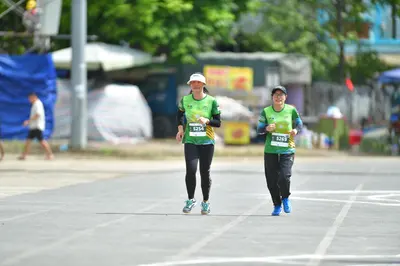 Marathon runner #5254, #5263: Runner 1: green jersey, black leggings, white cap, light-colored shoes