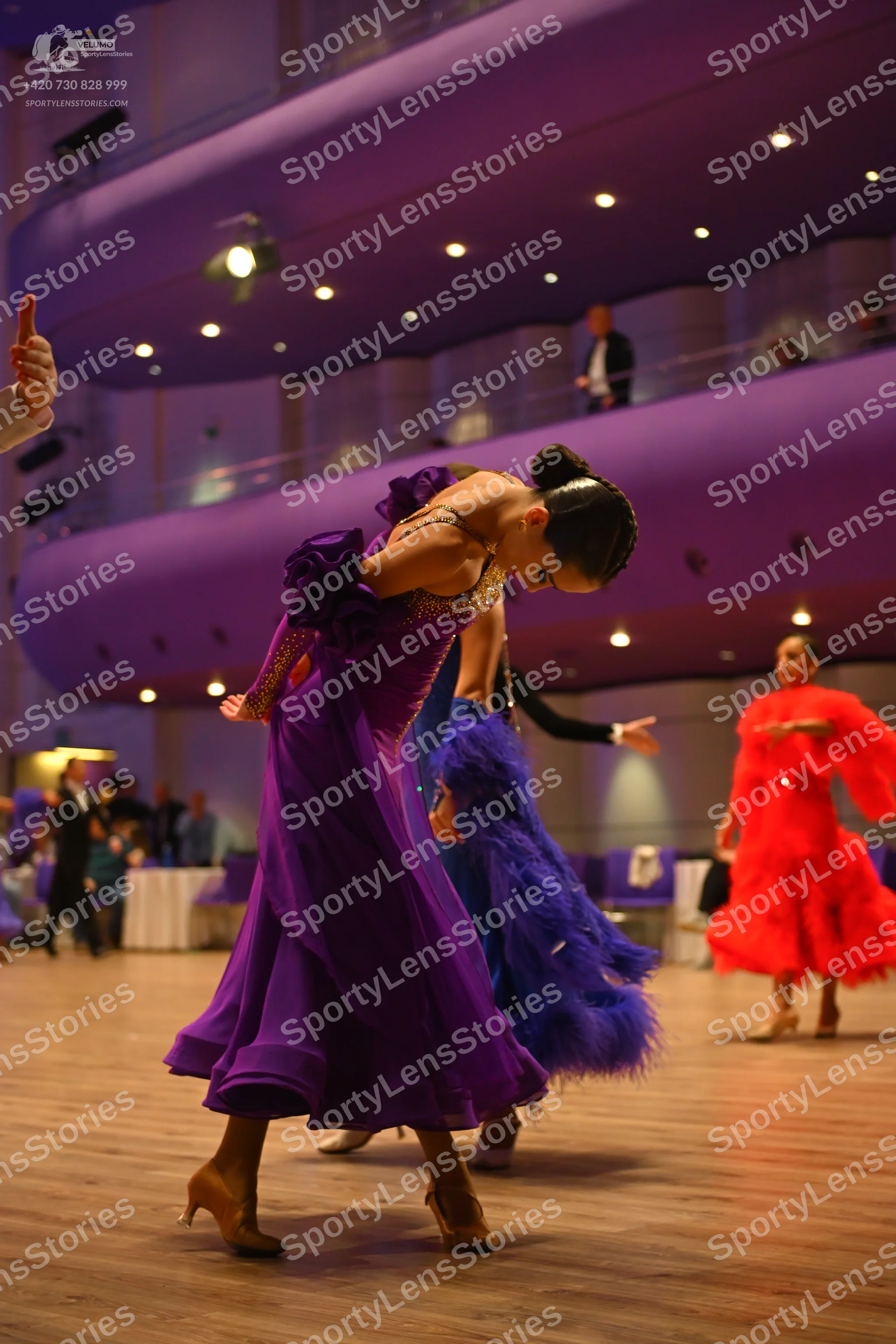 Dancesport competitor: Female dancer in foreground: purple ballgown with a sequined bodice and a flowin