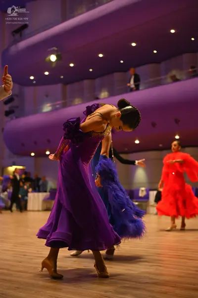 Dancesport competitor: Female dancer in foreground: purple ballgown with a sequined bodice and a flowin