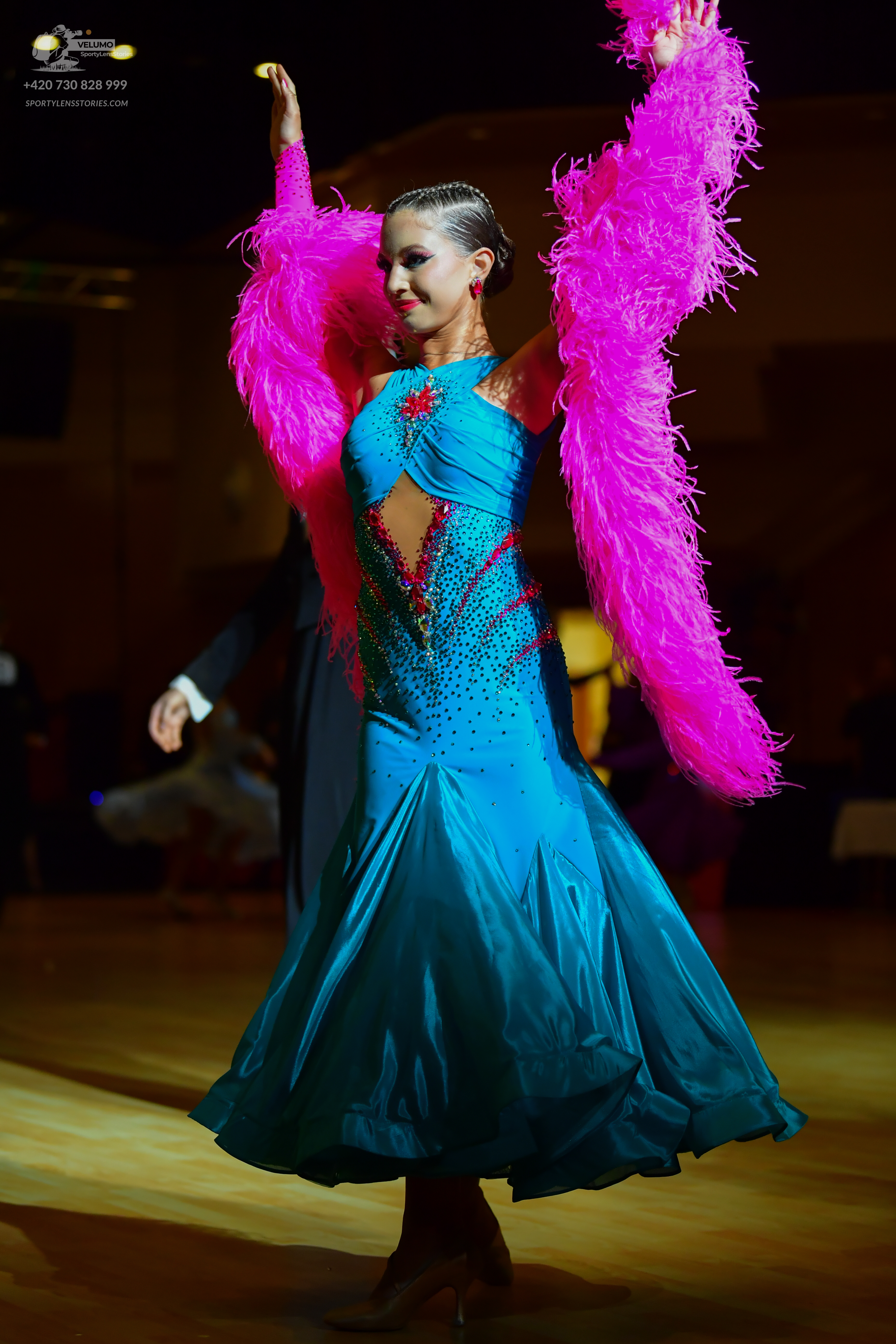 Dancesport competitor: Female dancer: blue ballroom gown with a sequined bodice, red accents, and large