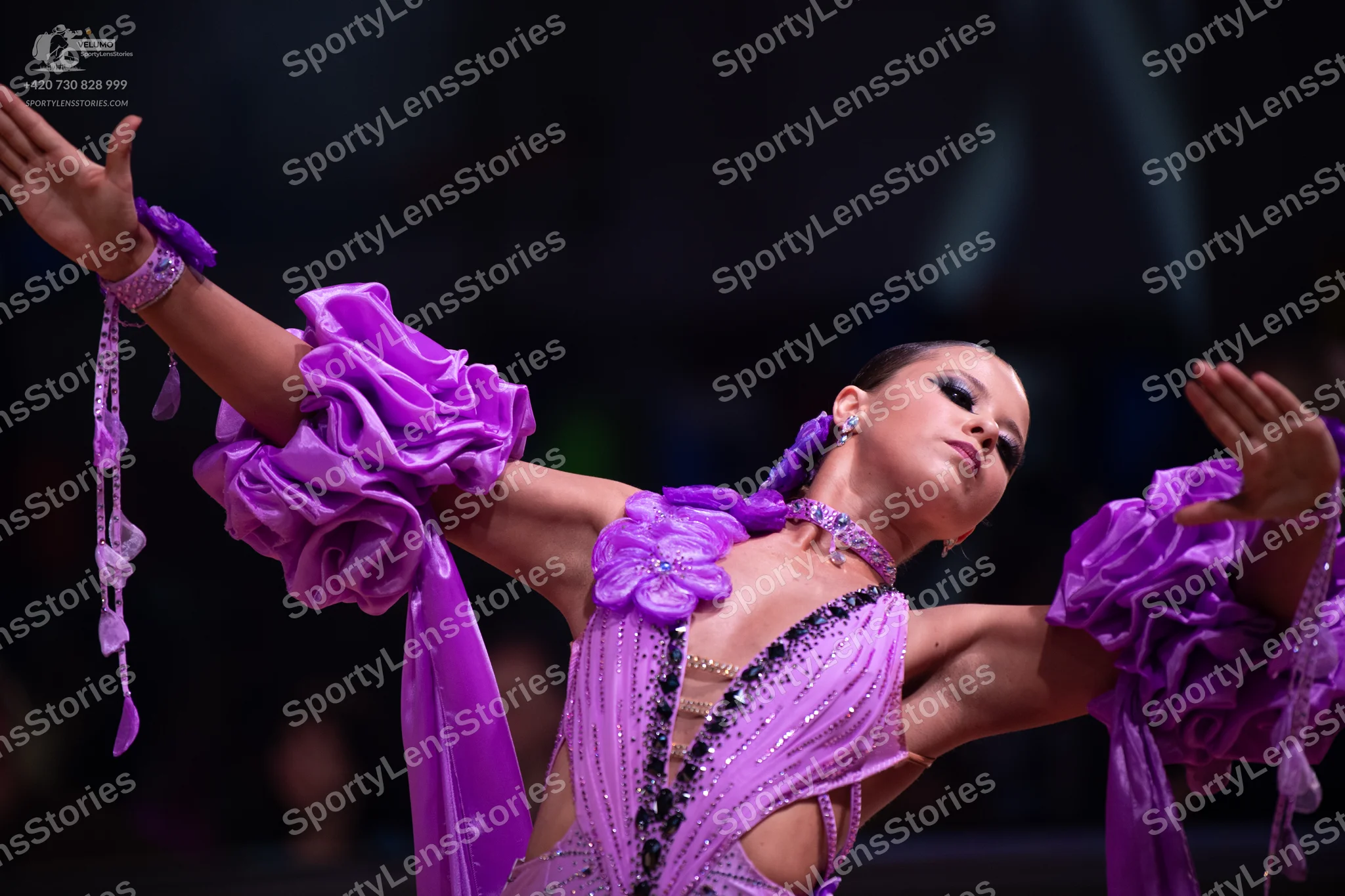 Dancesport competitor: Female dancer: purple latin dress with large ruffled sleeves, featuring sequins/
