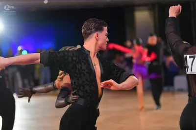 Dancesport competitor #47: Male dancer in foreground: black patterned long-sleeved shirt and black trousers