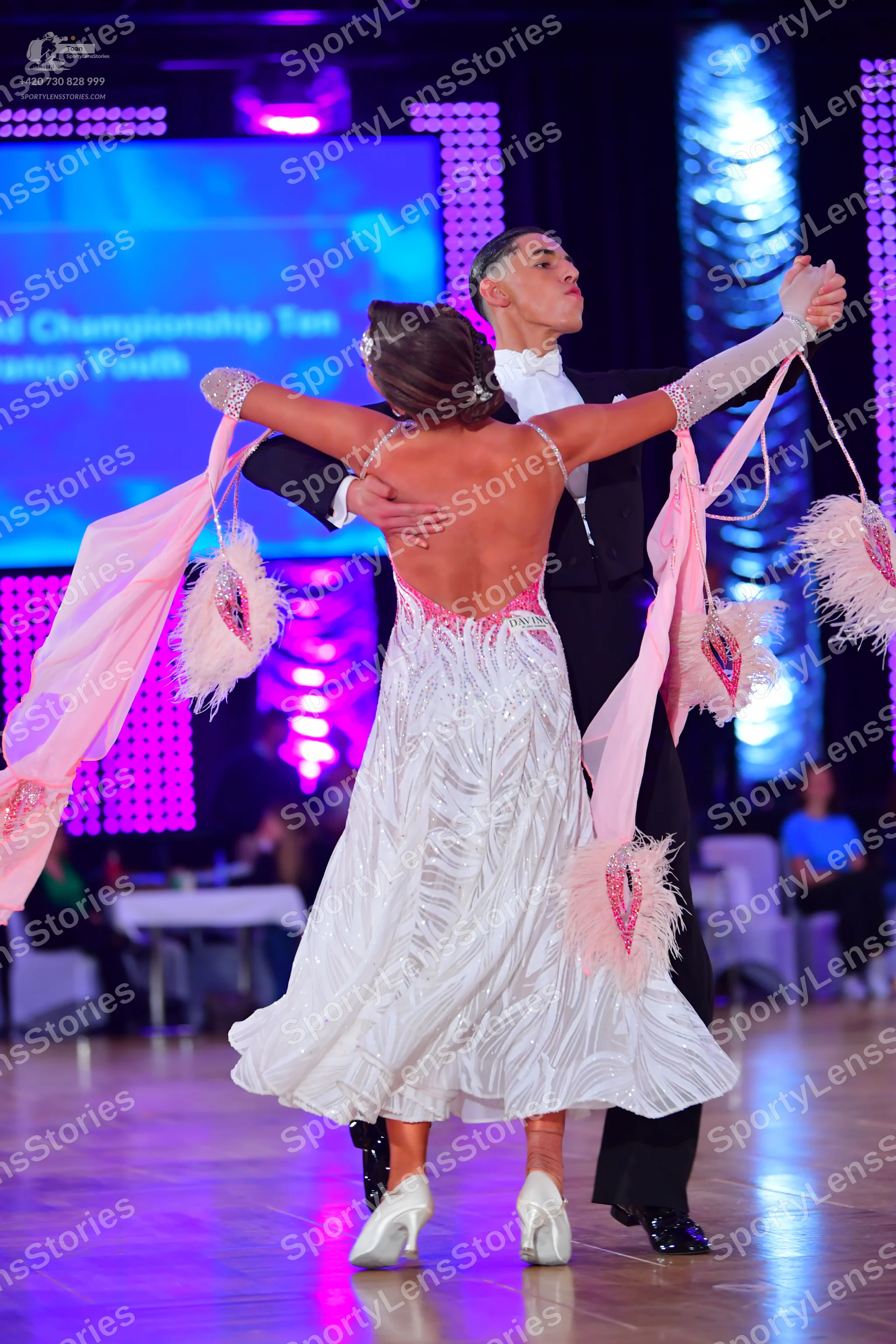 Dancesport competitor: Female dancer: white backless ballroom dress with pink/peach feathery or petal-l