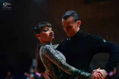 Dancesport competitor: Female dancer: silver/metallic long-sleeved, high-neck Latin dress with green an