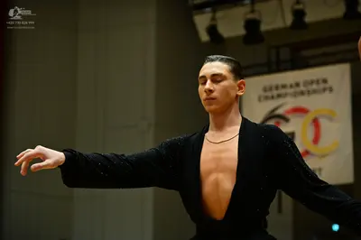 Dancesport competitor: Male dancer: black long-sleeved top with a deep neckline and subtle shimmering/s