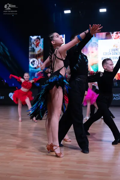 Dancesport competitor: Female dancer (foreground): black Latin dress with blue/teal fringe/sequin detai