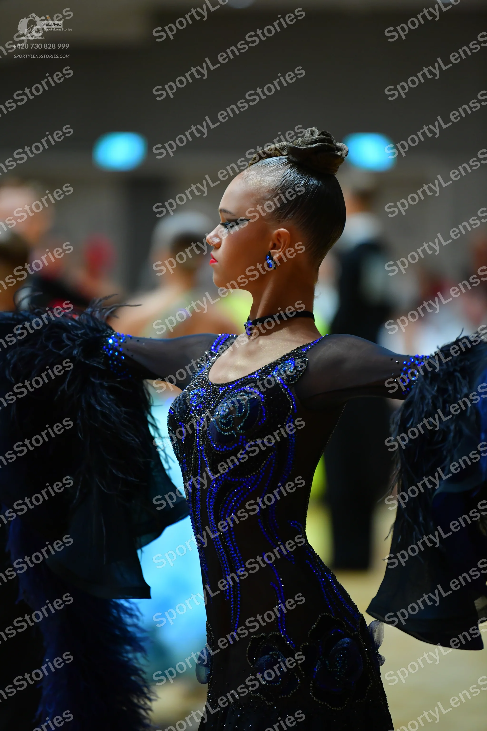 Dancesport competitor: Female dancer: black and blue sequined long-sleeved latin dress with large, volu