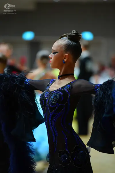 Dancesport competitor: Female dancer: black and blue sequined long-sleeved latin dress with large, volu