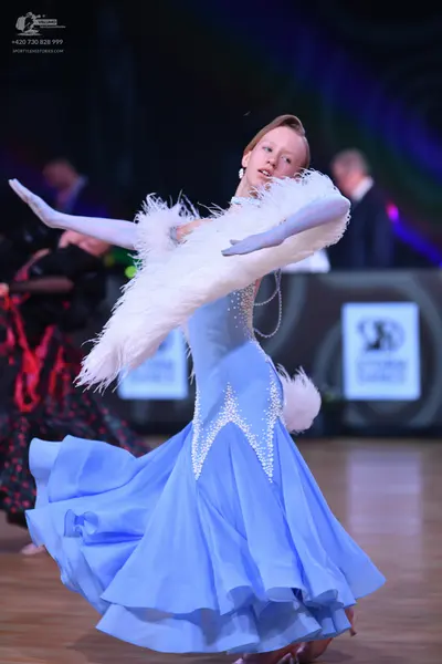 Dancesport competitor: Female dancer in foreground: light blue ballroom gown with silver rhinestones in
