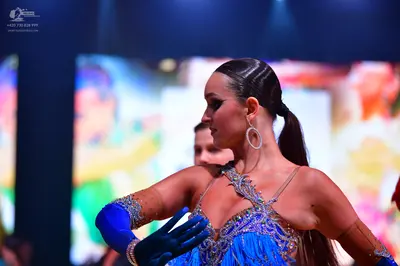 Dancesport competitor: Female dancer: blue Latin dress with sequins, beads, and fringe, and long blue g