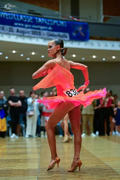 Dancesport competitor #830: Female dancer: bright pink latin dress with sequins and a flared, ruffled skirt,