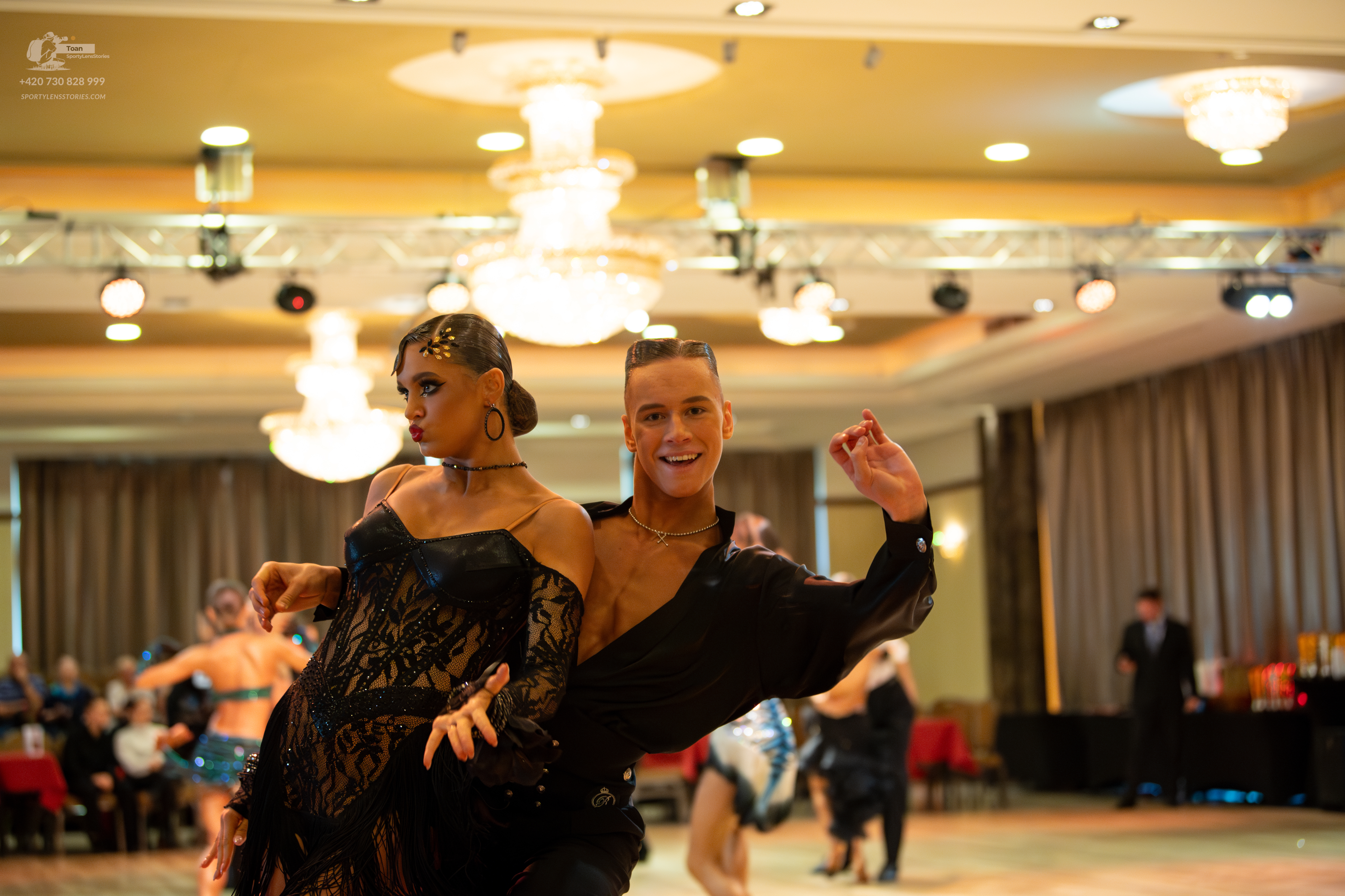 Dancesport competitor: Female dancer: black off-the-shoulder latin dress with intricate lace or embroid