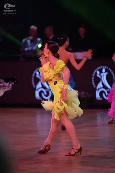 Dancesport competitor: Yellow dancer: yellow Latin dress with large yellow ruffles on the shoulders and