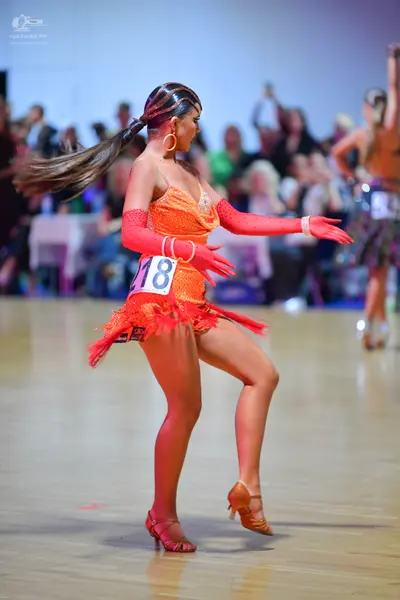 Dancesport competitor #18: Female dancer: orange latin dress with sequins and fringe, long orange gloves, a