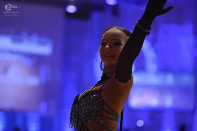 Dancesport competitor: Female dancer: black latin dance costume featuring beaded fringe and long black 