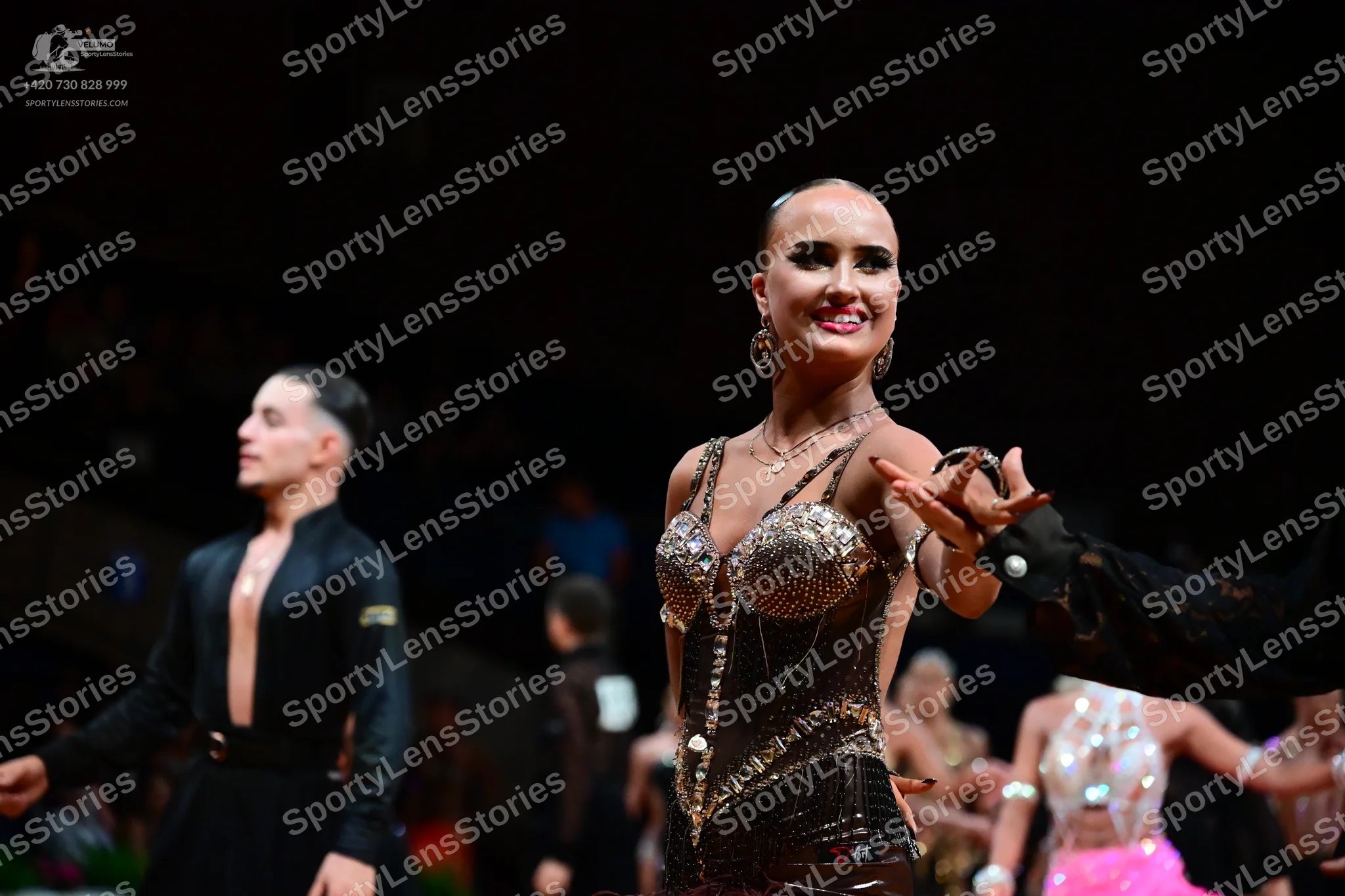 Dancesport competitor: Male dancer in foreground: black long-sleeved shirt and black trousers