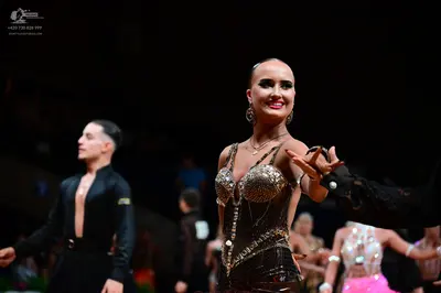Dancesport competitor: Male dancer in foreground: black long-sleeved shirt and black trousers