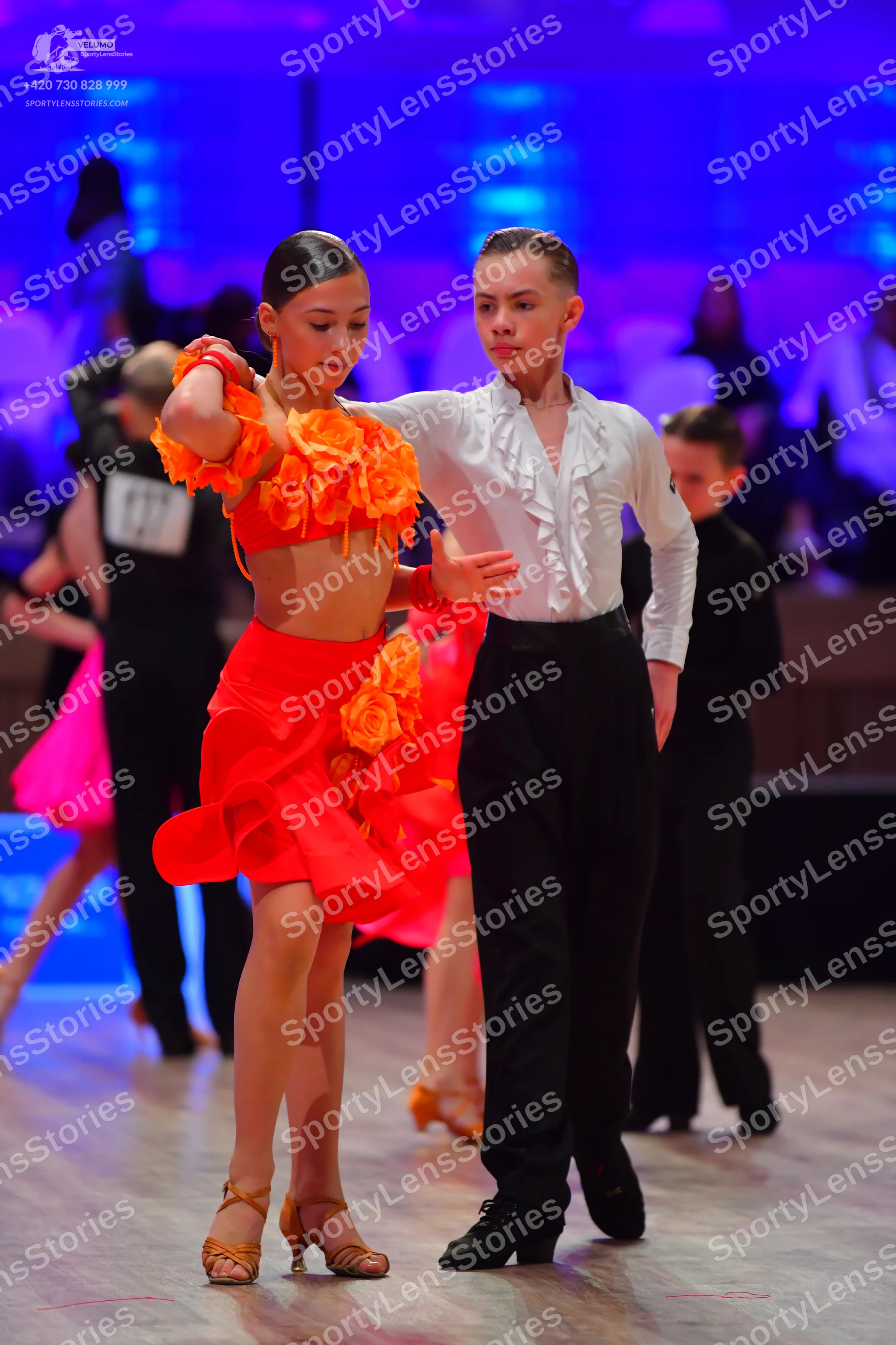Dancesport competitor: Female dancer: orange/red Latin dance costume with fabric floral embellishments