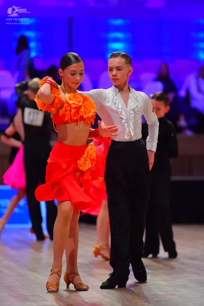 Dancesport competitor: Female dancer: orange/red Latin dance costume with fabric floral embellishments