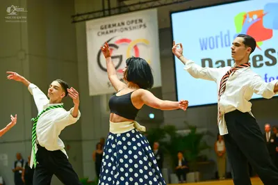 Dancesport competitor: Male dancer (left): white long-sleeved shirt, green and white striped tie, and b