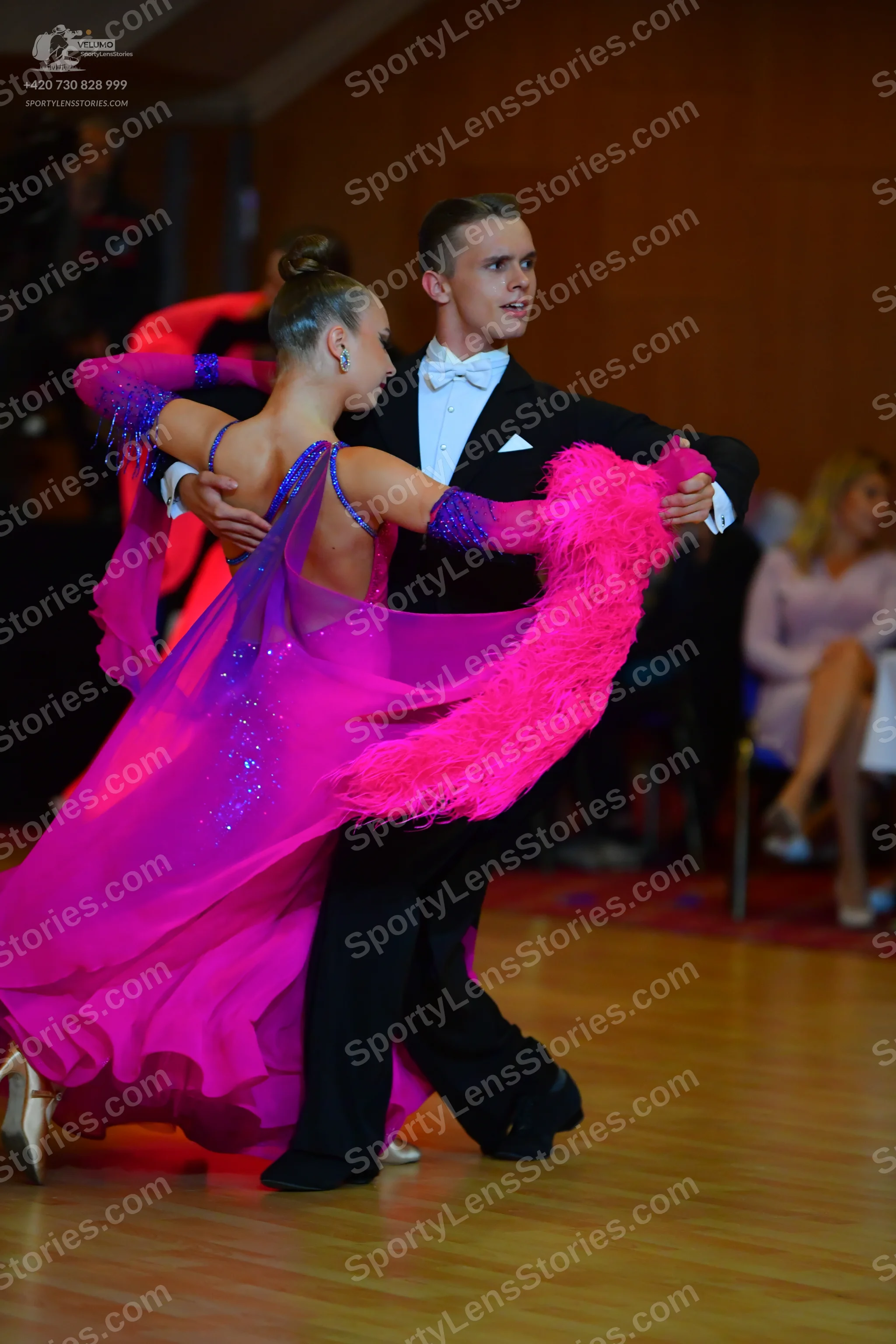 Dancesport competitor: Female dancer: bright pink latin dance dress with blue/purple sequined details o
