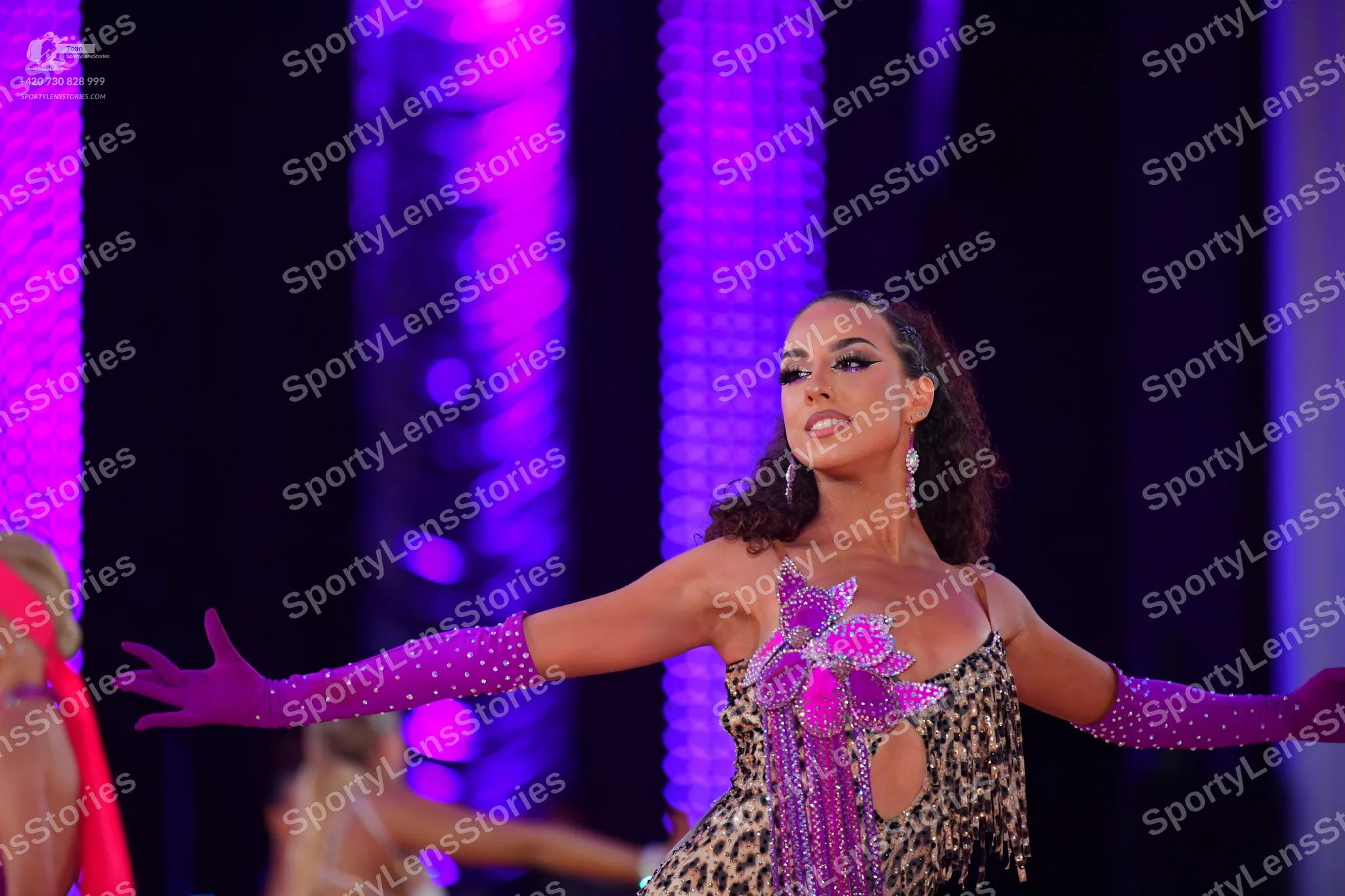 Dancesport competitor: Female dancer in foreground: leopard print latin dress with a large purple sequi