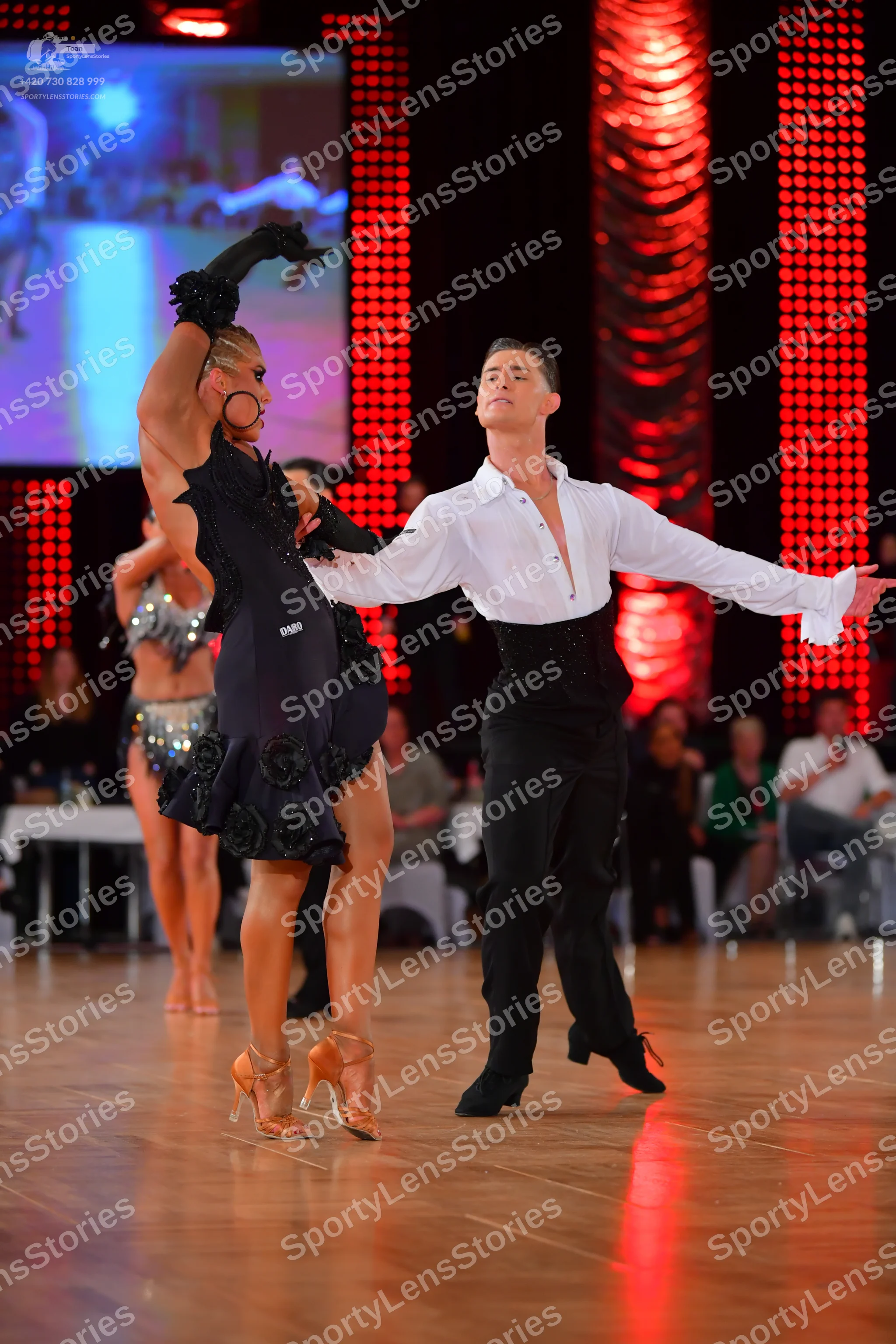 Dancesport competitor: Female dancer: black Latin dance dress with floral embellishments, long black gl