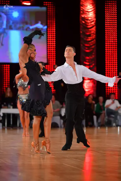 Dancesport competitor: Female dancer: black Latin dance dress with floral embellishments, long black gl
