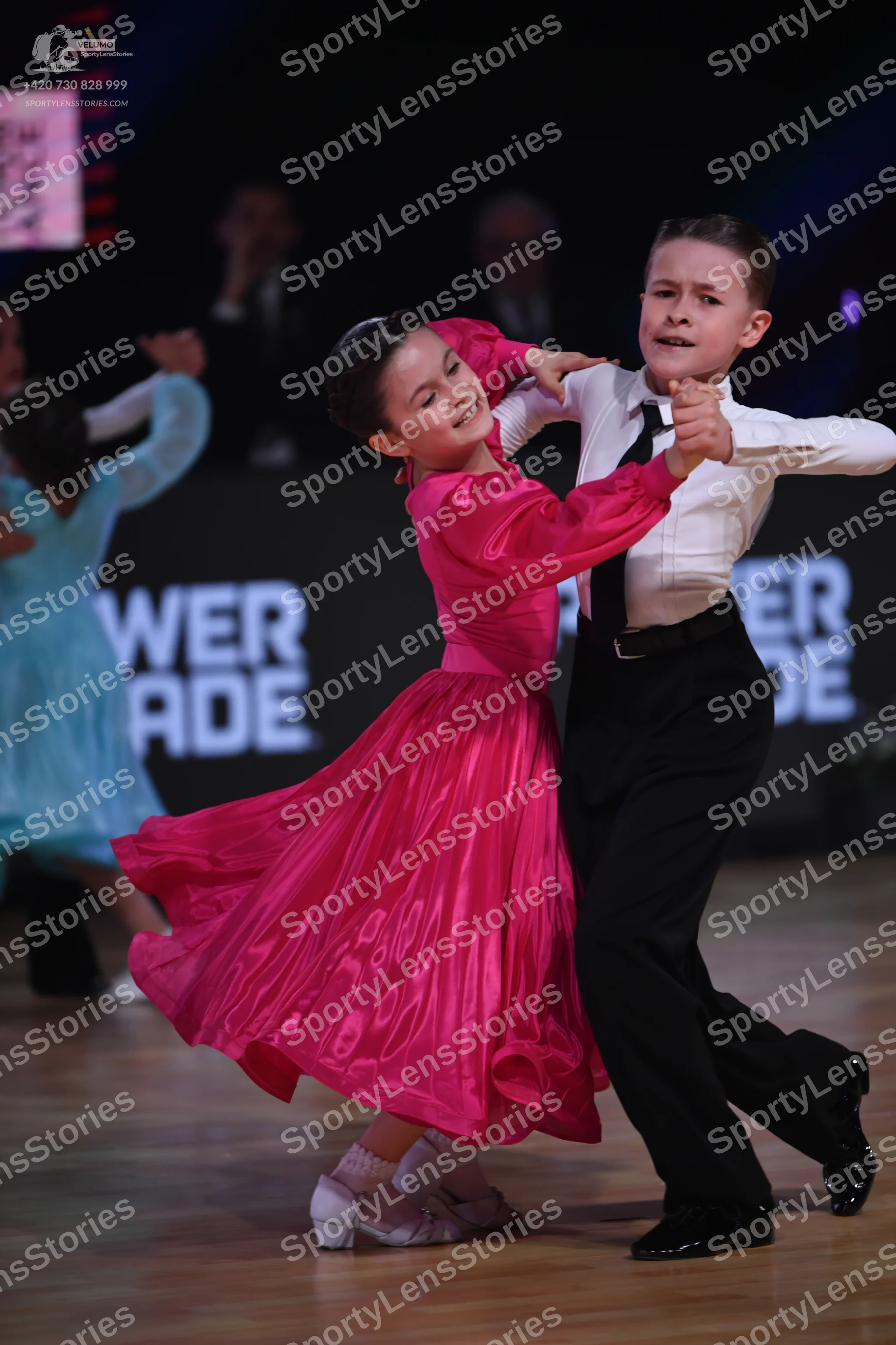 Dancesport competitor: Female dancer: bright pink satin-like long-sleeved dress with a full skirt