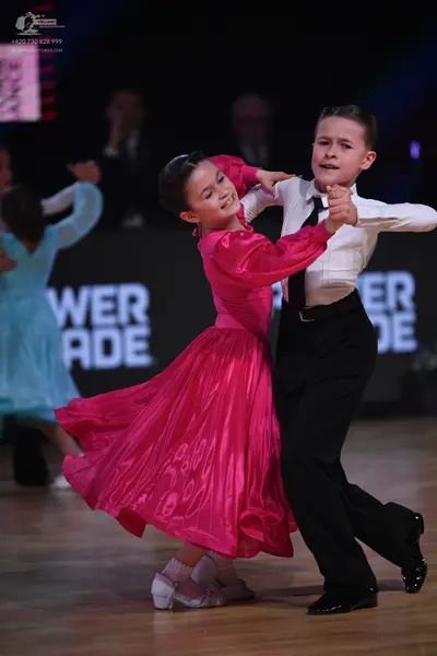 Dancesport competitor: Female dancer: bright pink satin-like long-sleeved dress with a full skirt