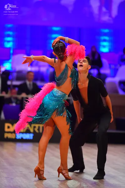 Dancesport competitor: Female dancer: teal Latin dance dress with sequins and long pink fringe