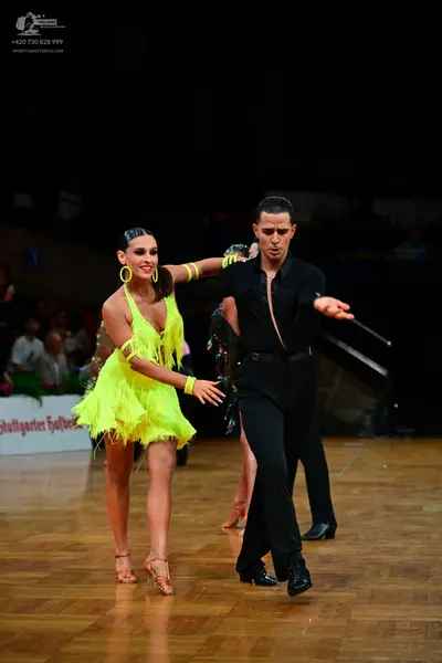 Dancesport competitor: Female dancer: bright yellow Latin dress with fringe and large yellow hoop earri