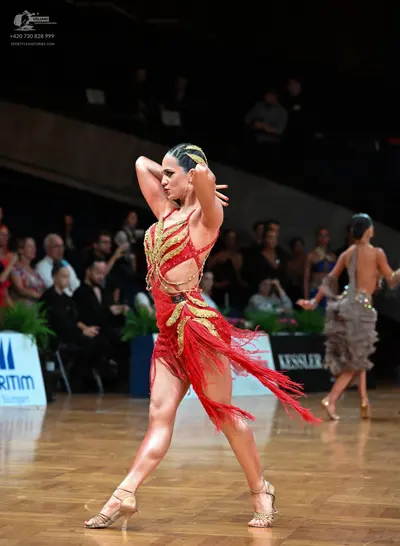 Dancesport competitor: Female dancer 1: red Latin dress with gold sequin patterns and red fringe