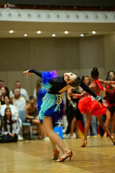 Dancesport competitor #81: First dancer: black long-sleeved latin dance dress with a colorful skirt featuri