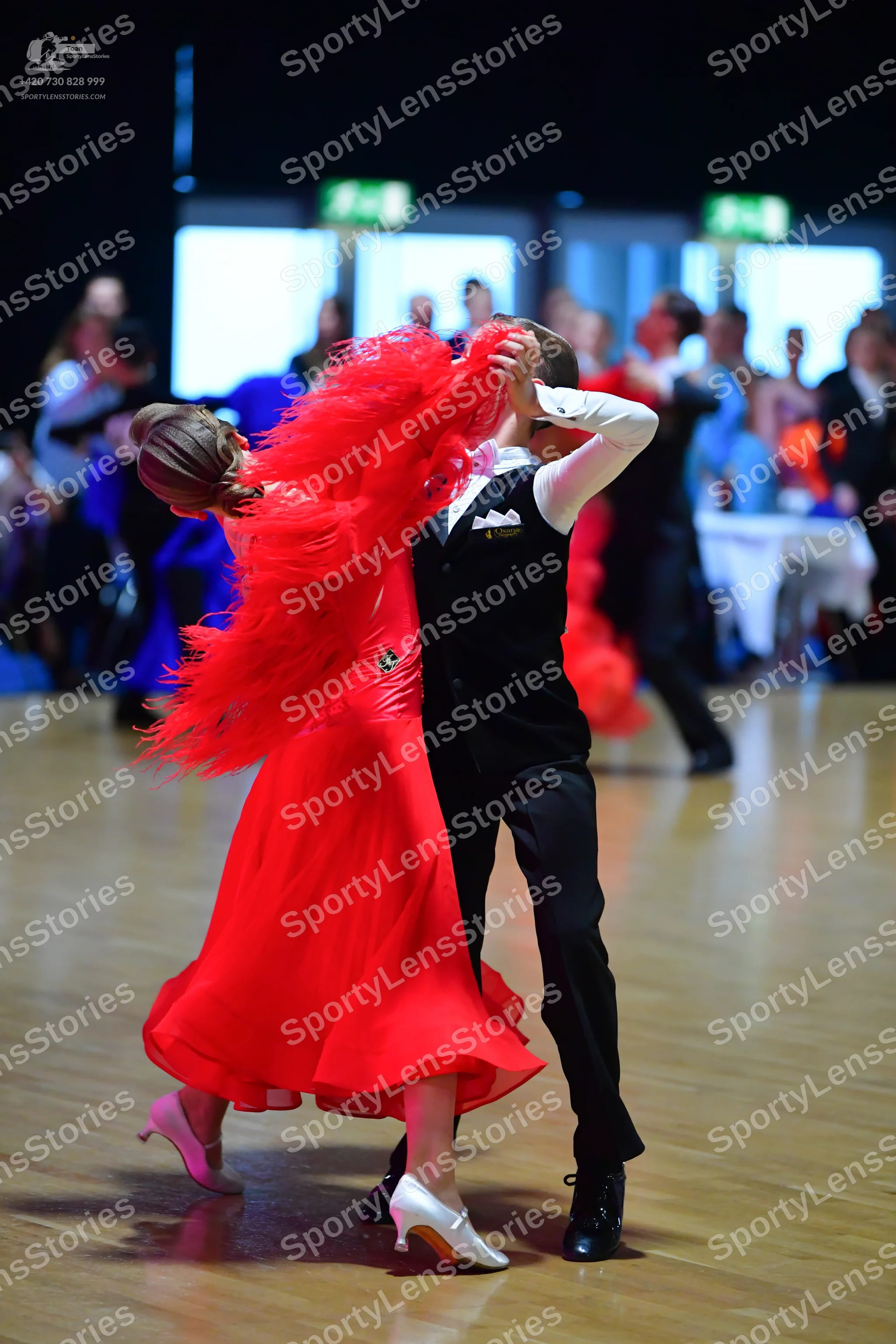 Dancesport competitor: Female dancer: red dress with voluminous red feathers or long fringe and a flowi
