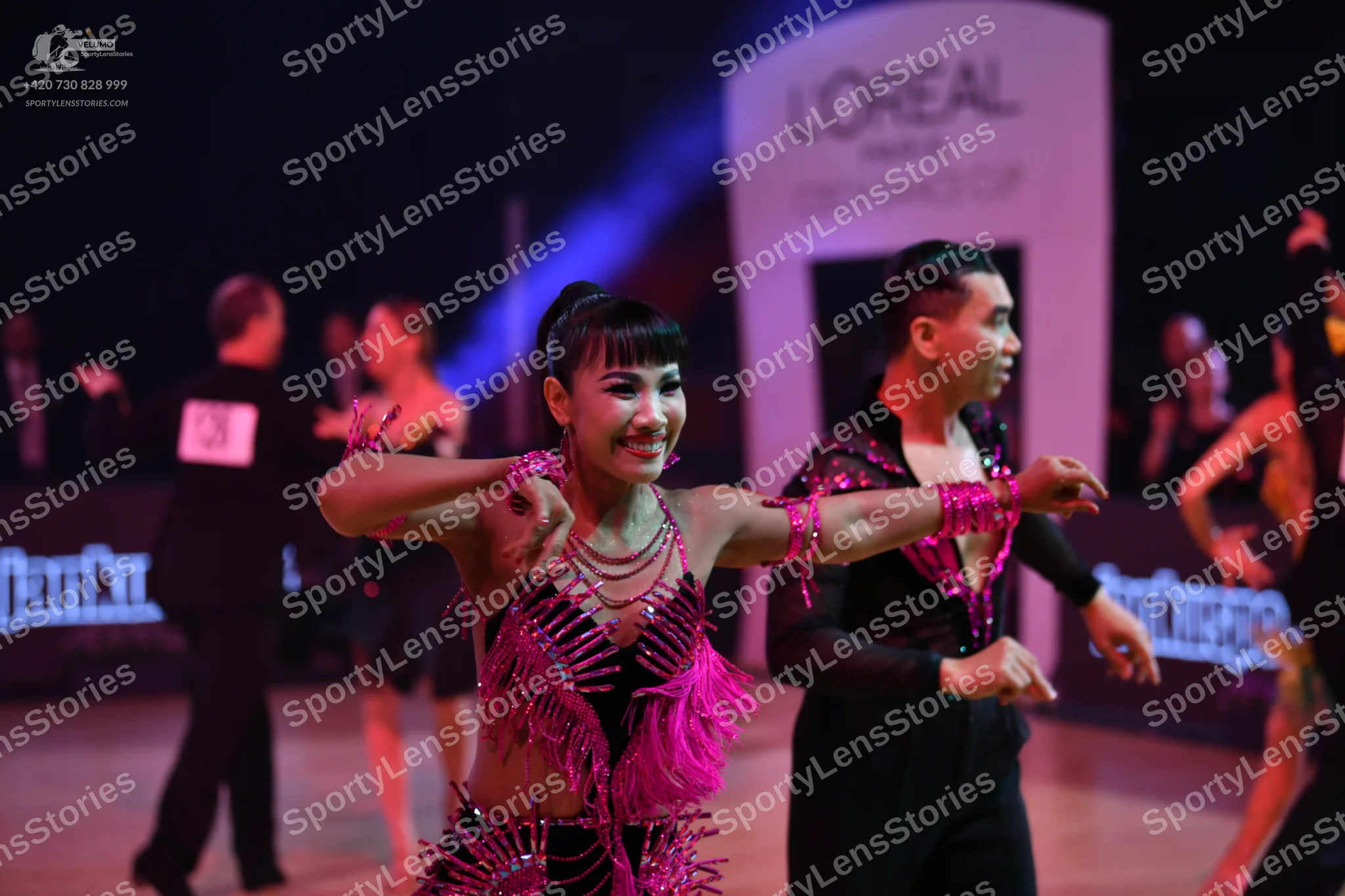 Dancesport competitor: Female dancer: bright pink Latin dance costume with heavy fringe and sequins