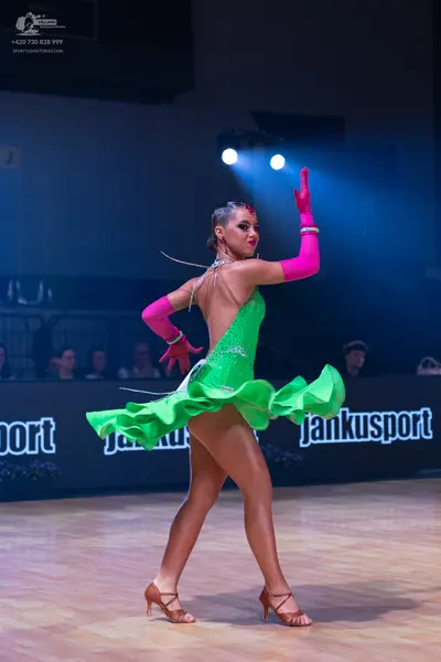 Dancesport competitor: Female dancer: green Latin dance dress with a ruffled skirt and decorative stran