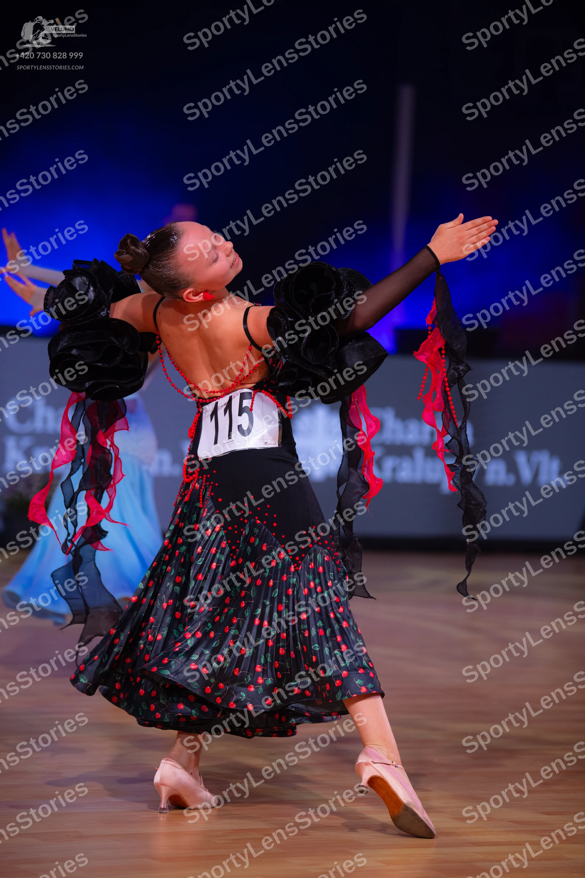 Dancesport competitor: Female dancer: black Latin dance dress with large black ruffled sleeves, a black