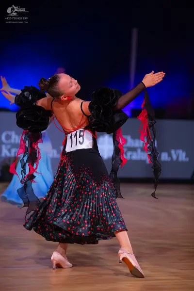 Dancesport competitor: Female dancer: black Latin dance dress with large black ruffled sleeves, a black