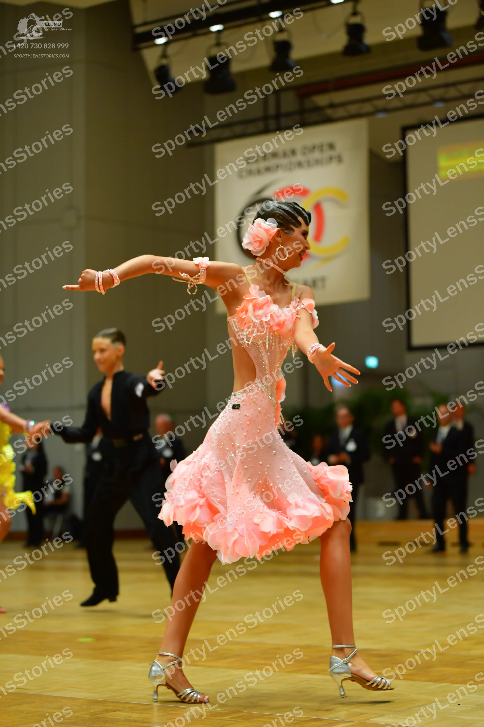 Dancesport competitor: Female dancer: light pink Latin dance dress with a ruffled, petal-like skirt and