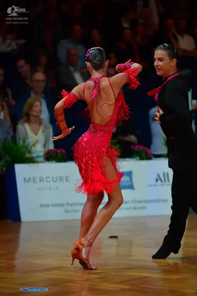 Dancesport competitor: Female dancer: red Latin dress with sequins and long fringe