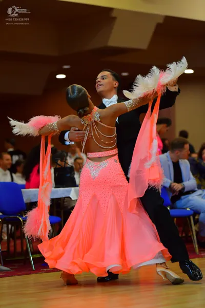 Dancesport competitor: Female dancer: coral-colored latin dress with a sequined bodice, open back with 