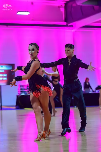 Dancesport competitor: Female dancer: black latin dress with orange/red fringe and black wristbands