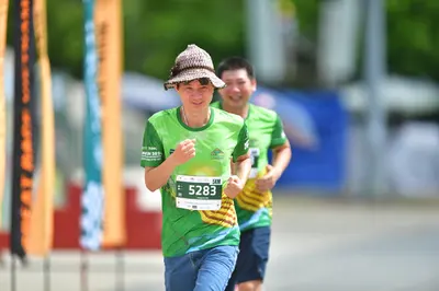 Marathon runner #5283: Runner 1: green jersey, blue shorts, patterned brown bucket hat