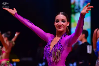 Dancesport competitor: Female dancer in foreground: magenta long-sleeved latin dress with purple sequin
