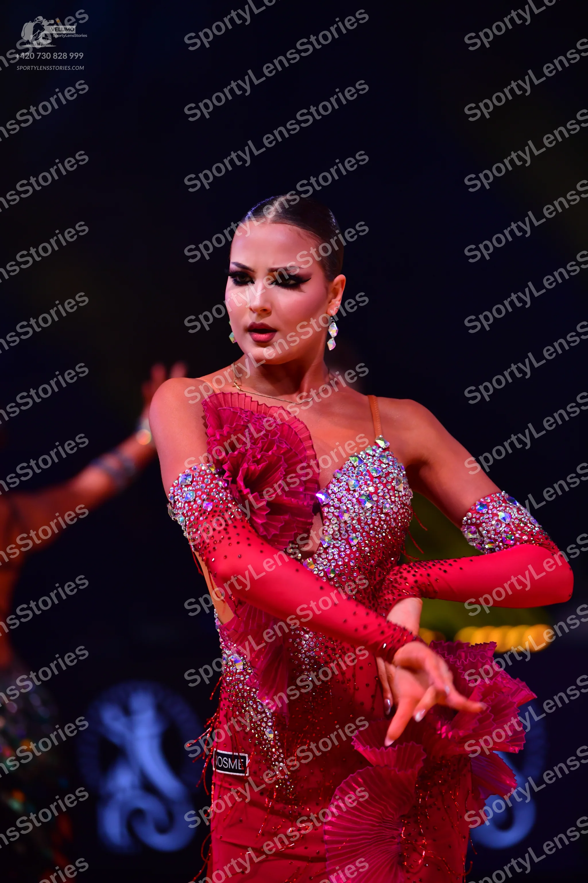 Dancesport competitor: Female dancer: red Latin dress with heavy sequin embellishments, large ruffles o