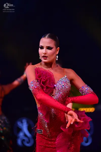 Dancesport competitor: Female dancer: red Latin dress with heavy sequin embellishments, large ruffles o