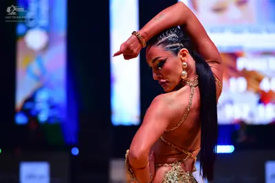 Dancesport competitor: Female dancer: gold-colored, heavily sequined Latin dance costume with a backles