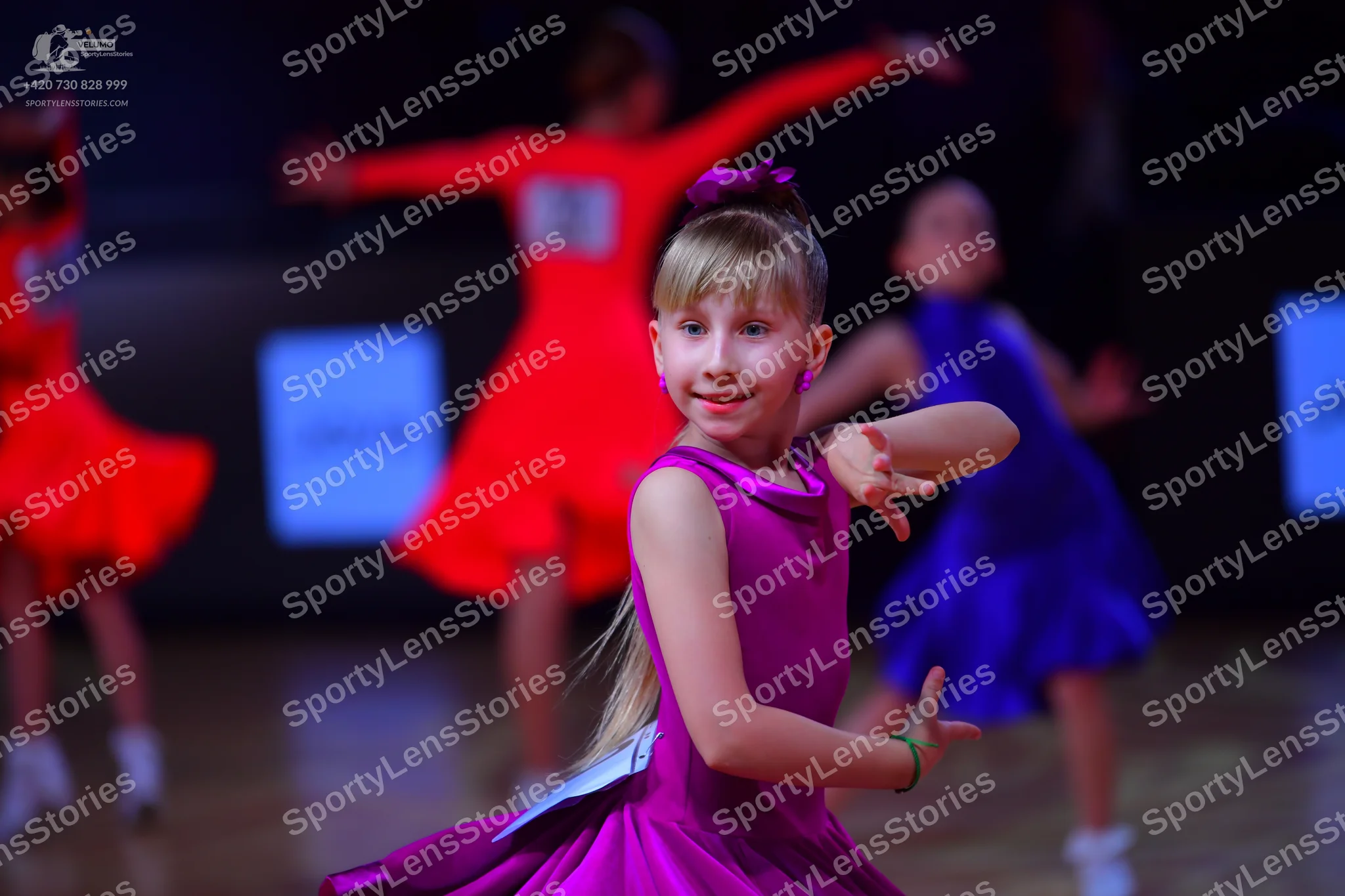 Dancesport competitor: Female dancer in foreground: magenta/purple latin dress, sleeveless, smooth fabr