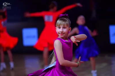 Dancesport competitor: Female dancer in foreground: magenta/purple latin dress, sleeveless, smooth fabr